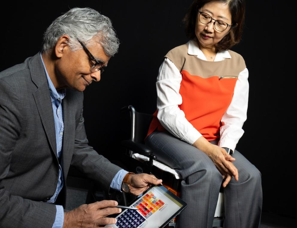 Sundaresan Jayaraman (left) looks at pressure data from fabric sensors he developed with Sungmee Park, who is seated in their prototype wheelchair system.