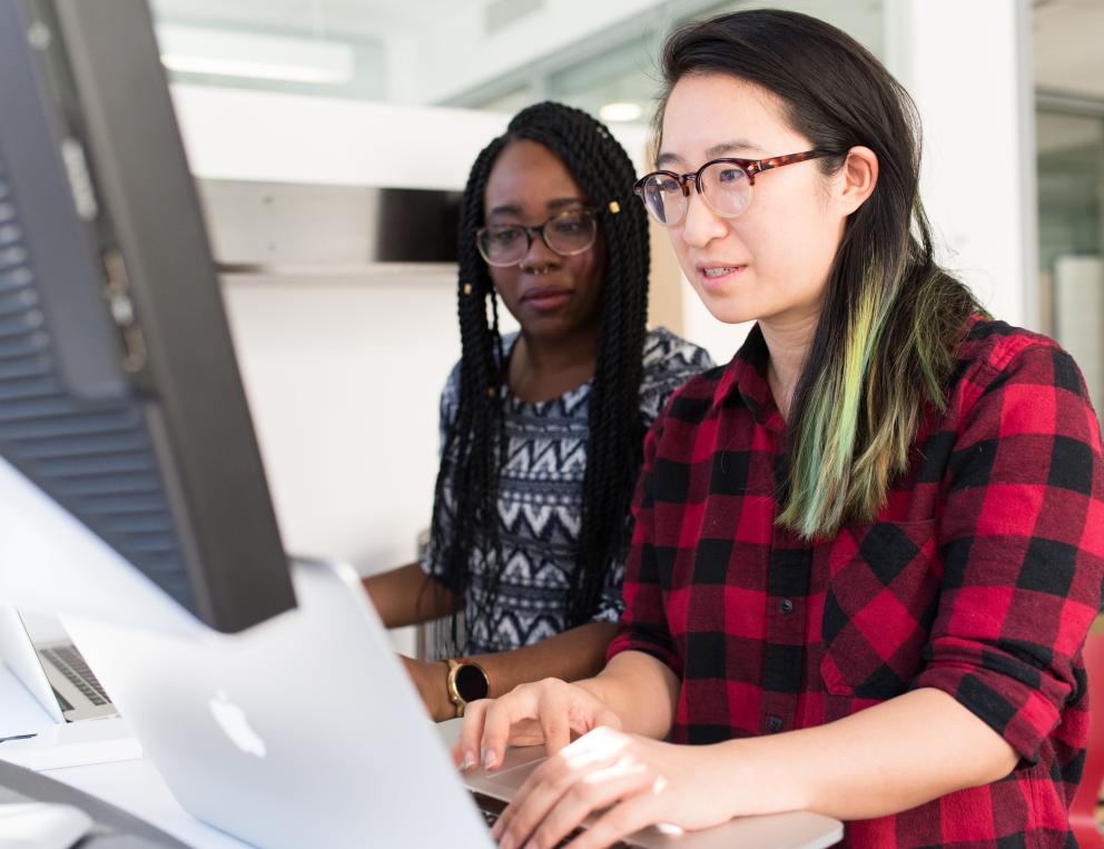 Two women working on a computer together.