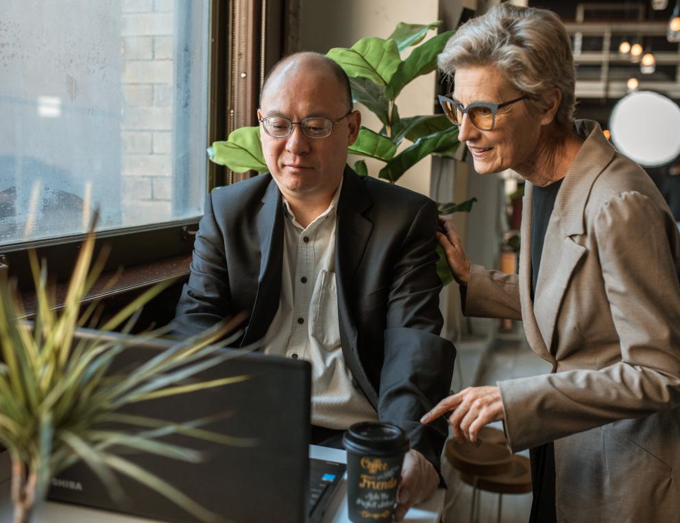 Two people working on a computer together.