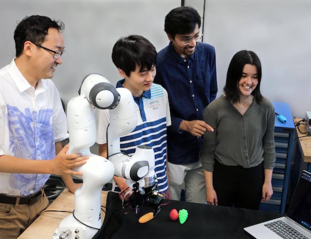 Professor Ye Zhao (GT-ME), high school intern Matthew Zhu, graduate student Chaitanya Mehta, and high school intern Christian Hable with the lab's robotic arm with tactile sensors.